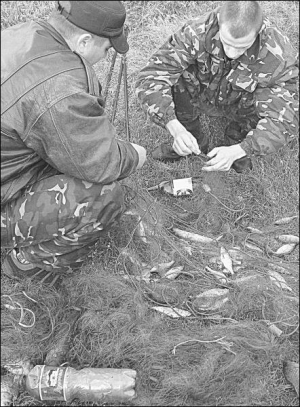 29 мая в селе Глубочек Тростянецкого района во время рейда задержали трех браконьеров из поселка Крыжополь. Инспектор областной рыбоохраны Роман Додчук (справа) вытягивает из сетки рыбу. Второй мужчина — задержанный