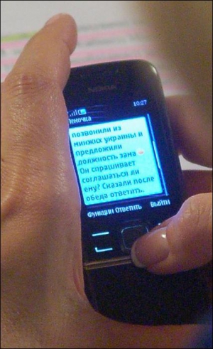 Людмила Денисова читає текст повідомлення на своєму мобільнику