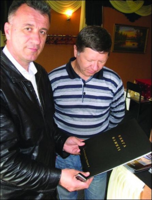 Михаил Панькив (слева) вместе с заведующим кафе ”Поминальное” просят клиентов записывать свои отзывы об обслуживании в Книгу памяти. В ней только благодарности