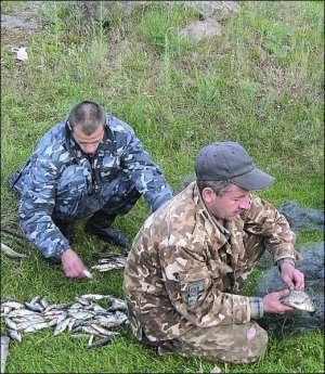 27 травня 2009 року на Ладижинському водосховищі інспектор Вінницької обласної рибоохорони Роман Додчук (справа) разом з браконьєром витягують із сітки рибу і перераховують її для оформлення штрафу