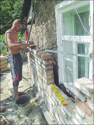 Строитель выкладывает кирпичом стену дома жительницы Полтавы Веры Тагиевой. Из-за сырости старая кирпичная кладка отпала