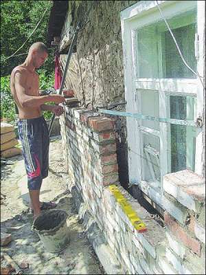 Будівельник викладає цеглою стіну будинку полтавки Віри Тагієвої. Через сирість стара цегляна кладка відпала