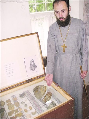 Священик Павло Петльований у приміщенні музею Немирівського жіночого монастиря показує рештки трипільського посуду та закам’яніле дерево