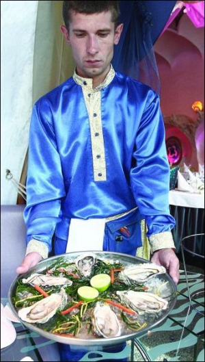 Официант столичного ресторана ”Авалон” Андрей Кузьменко подает французских устриц жилардо. Они выложены на тарель со льдом и водорослями, посередине — половинки лайма. Устрица стоит 84 гривни