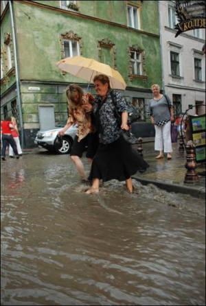 На вулиці Сербській у центрі Львова люди переходять дорогу вбрід. Злива із сильним вітром тривала півгодини