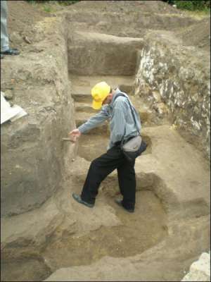 Житель Гадяча Роман Столетченко на раскопках рассматривает кость, которая торчит из стены подземелья храма