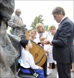 Президент Віктор Ющенко (праворуч) із дружиною та трьома дітьми говорить із хлопчиком-бандуристом біля пам’ятника українським гетьманам у Батурині