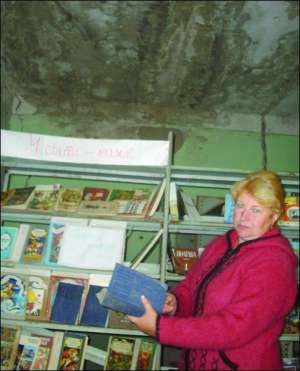 Бібліотекар із села Погреби Глобинського району Світлана Ткаченко показує книжки. Їх обкладинки вкрилися цвіллю, бо будинок культури не опалюють. На стелі видно слід від протікання, вона осипається, утворюються тріщини