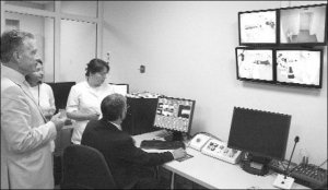 Лучевой терапевт Андрей Леонович (за компьютером) показывает через камеры, установленные в операционной, кибернож для удаления онкоопухолей. Позади - руководитель киберклиникы, бывший министр здравоохранения Юрий Спиженко