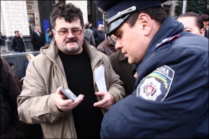 Нардеп от Компартии третьего созыва Владимир Пустовойтов показывает свое удостоверение милиционеру во время вчерашнего протеста на Майдане Независимости