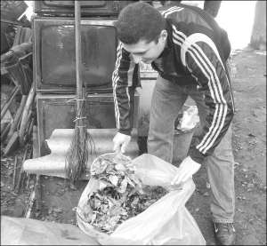 Вінничанин Тимур Кравченко збирає листя у власний пакет для сміття по вулиці Кірова. Пакет у квартальному комітеті йому ще не давали