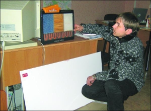 Представник фірми СТН Олексій Болотов показує білий електрорадіатор та різнокольові зразки матів для теплої підлоги