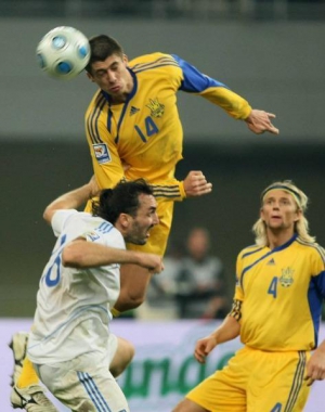 Защитник сборной Украины Евгений Хачериди (№14) выигрывает воздушную борьбу у Сотириса Кирякоса. Хачериди впервые сыграл на этнической родине, его отец — грек