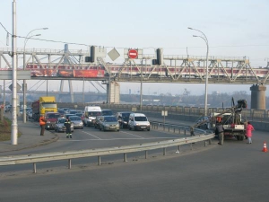 9.00, вівторок, 17 листопада. Зйомки реклами на перехресті вулиць Електриків і Набережно-Рибальської в Києві. Праворуч —вантажівка з краном і кінокамерою. Ліворуч — інспектор Державтоінспекції зупинив рух на трьох смугах, аби знімальна група вибрала вдали