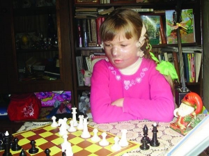 Настя Гордиенко из города Каменка Черкасской области играет в шахматы. На лице у нее прозрачная маска, которая помогает обожженной коже быстрее восстановиться