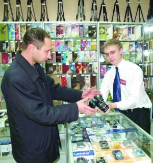 Продавец оптово-розничного центра рассказывает посетителю о технических характеристиках фотоаппарата