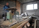 Николай Письменный в новом хозяйственном здании режет деревянные брусья. Помещение вскоре будут использовать под склад старой мебели