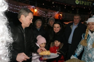 Мэр Киева Леонид Черновецкий на открытии катка дает кусок глазированного пирога с яблоками стоящей рядом девочке