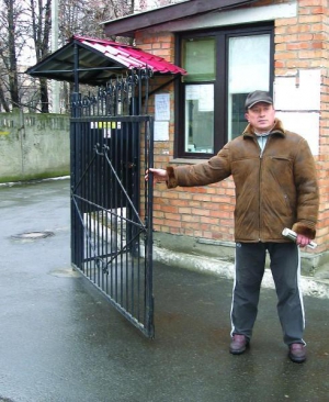 Мешканець будинку №39 по вулиці Острозького у Вінниці Леонід Лаврик зачиняє ворота, що перекривають дорогу у двір. Чоловік безкоштовно чергує у добровільній охороні. Представник кожної з 96 квартир має почергувати