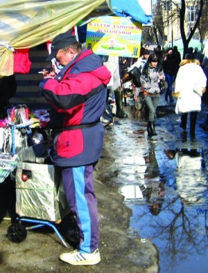 На Центральному базарі Черкас  біля ятки чоловік розраховується за покупку. Одночасно курить цигарку й шукає гроші