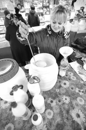 Оксана Решетило наливает домашнее молоко в одноразовую тару на львовском рынке Шувар в понедельник утром. Она привозит его продавать из Ривненской области