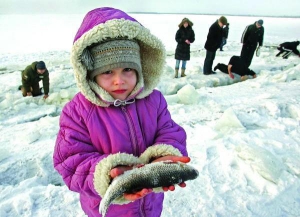 Девочка показывает рыбу, пойманную в трещинах льда на Киевском водохранилище неподалеку от Вышгорода в субботу, 13 марта