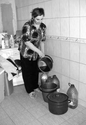 Мешканка будинку 38а по вулиці Скалецького у Вінниці Олена Ковальська набирає воду у відра та пластикові пляшки. Через поганий тиск часто пропадає вода
