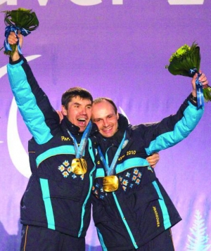 Биатлонист Виталий Лукьяненко (слева) и его сопровождающий Владимир Иванов празднуют получение золотой награды в гонке преследования на три километра