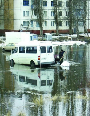 Мужчина на автостоянке ”Автопарк ТОР” на окраине Кременчуга в понедельник расчищает лопатой от снега и мусора стоковые канавы, чтобы сошла вода. Подтопило шесть авто