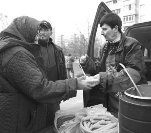 Работники ”Социального патруля” кормят беспризорную на улице Кибальчича в Киеве