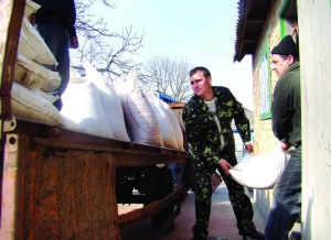 Віктор Бобик (у центрі) вантажить добрива для внесення на поля з овочами