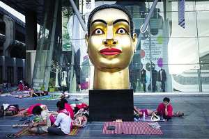 Антиправительственные демонстранты, которых еще зовут ”красными рубашками”, просыпаются утром возле статуи Будды перед входом в универсам ”Централ Ворлд Плаза” в Бангкоке, столице Таиланда