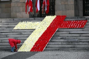Дівчина у польському місті Катовіце 17 квітня 2010 року знімає на відеокамеру килим із квітів, зроблений у вигляді червоно-білого хреста. Цього дня Польща прощалася із президентом Лехом Качинським та іншими загиблими в авіакатастрофі під Смоленськом 10 кв