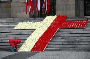 Дівчина у польському місті Катовіце 17 квітня 2010 року знімає на відеокамеру килим із квітів, зроблений у вигляді червоно-білого хреста. Цього дня Польща прощалася із президентом Лехом Качинським та іншими загиблими в авіакатастрофі під Смоленськом 10 кв