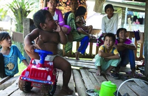 Арди Ризал с папиросой сидит на своей любимой игрушке — детской машине. Курит на веранде родительского дома в индонезийском поселке Муси Баньюзин