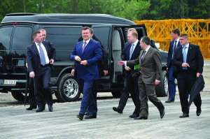 Президент Виктор Янукович с вице-премьером Борисом Колесниковым (сзади справа налево), губернатором Львовщины Василием Горбалем в окружении шести охранников в четверг идут осматривать новый львовский стадион. У двух охранников — зонтики, хотя дождя не был