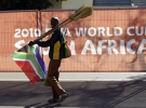 Уличный торговец продает метлы за ограждением стадиона в столице ЮАР — Претории. Большинство населения Африки живут за чертой бедности