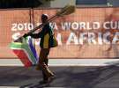 Вуличний торговець продає мітли за огорожею  стадіону в столиці ПАР — Преторії. Більшість населення Африки живе за межею бідності