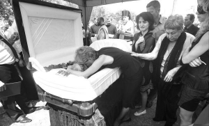 Ірина Зінченко прощається зі своїм чоловіком, депутатом Київради від БЮТу Олександром Зінченком. Його поховали 11 червня на Байковому кладовищі. Позаду ліворуч — їхня донька Олександра, крайня праворуч — донька Катерина