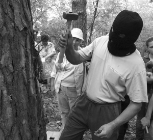 Столичний еколог забиває у сосну в Чернечому лісі за п’ять кілометрів від Києва 15-сантиметровий цвях. Так захищає дерево від вирубки. Одягнув чорну маску, бо такі дії незаконні