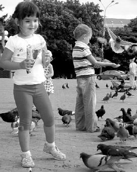 Деть кормят голубей возле драмтеатра в центре Мариуполя. В этом городе на берегу Азовского моря живут 478 тысяч человек