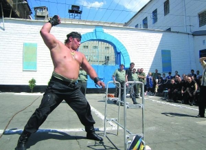 Силач Дмитрий Халаджи готовится разорвать рукой натянутую железную цепь. Он выступил перед заключенными в донецком следственном изоляторе