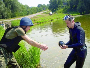 Рятувальник Микола Швидкий передає начальнику групи піротехніків Сергієві Бойку снаряд, який витяг зі ставка в селі Оляниця Тростянецького району Вінниччини