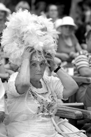 Літня жінка приміряє шапочку з гусиного пір’я на конкурсі капелюшків у столичному Маріїнському парку. Лобова частина шапочки оздоблена декоративними камінцями