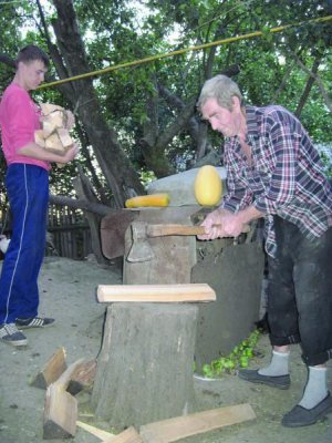 69-річний Василь Тимошенко (праворуч)  рубає дрова на своєму подвір’ї у селищі Цвіткове Городищенського району. Його онук 17-річний Андрій заносить їх до сараю 