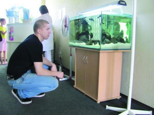 Черкащанин Олександр Тимко годує рибок у приймальній одного зі стоматологічних кабінетів міста. В акваріумі відтворили атмосферу африканського озера Танганьїка 