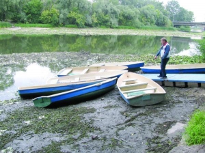 Працівник прокатної човнової станції в мікрорайоні Герівка в Полтаві Віктор Павельчук стоїть біля плавзасобів. Через спускання води в річці вони опинилися на суші