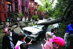 Жители района Бруклин в Нью-Йорке стоят возле автомобиля ”мицубиши”, на который во время шторма 16 сентября упало дерево. Страховые компании уже начали возмещать убытки