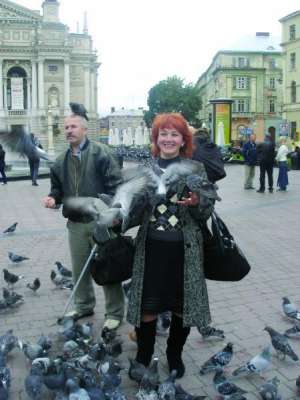 Туристи фотографуються з ручними голубами біля Львівського оперного театру. Володимирові Кравчуку залишають на насіння по 5–10 гривень
