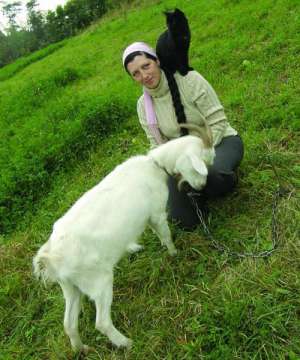 Наталия Кушнир гладит козу Белку и держит на плече кота Перфоратора на пастбище в селе Клещев на Виннитчине. В 2005 году она оставила работу в Киеве и купила в селе дом